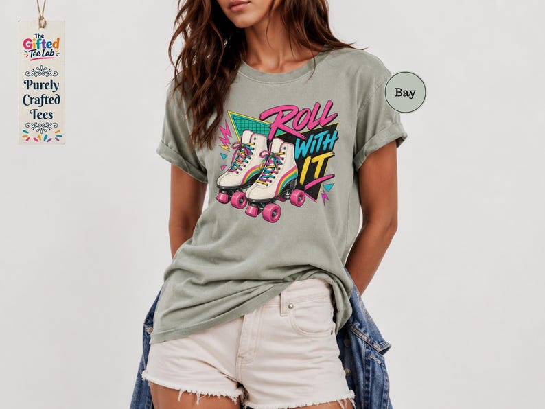 A woman wearing a gray t-shirt with a graphic design of roller skates and the text "Roll with it" printed on it.