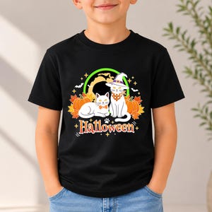 A graphic design featuring two black cats, one wearing a purple witch hat and orange bandana, sitting among pumpkins and autumn leaves under a full moon with the word Halloween below.