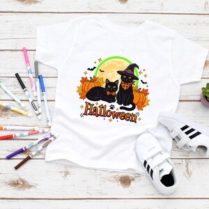 A graphic design featuring two black cats, one wearing a purple witch hat and orange bandana, sitting among pumpkins and autumn leaves under a full moon with the word Halloween below.