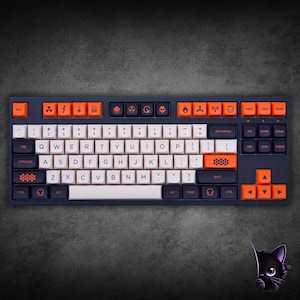 May include: A mechanical keyboard featuring a dark gray frame with a mix of off-white, dark gray, and bright orange keycaps. The top row includes orange keys with various hazard and warning symbols, while other keys feature custom icons and text.
