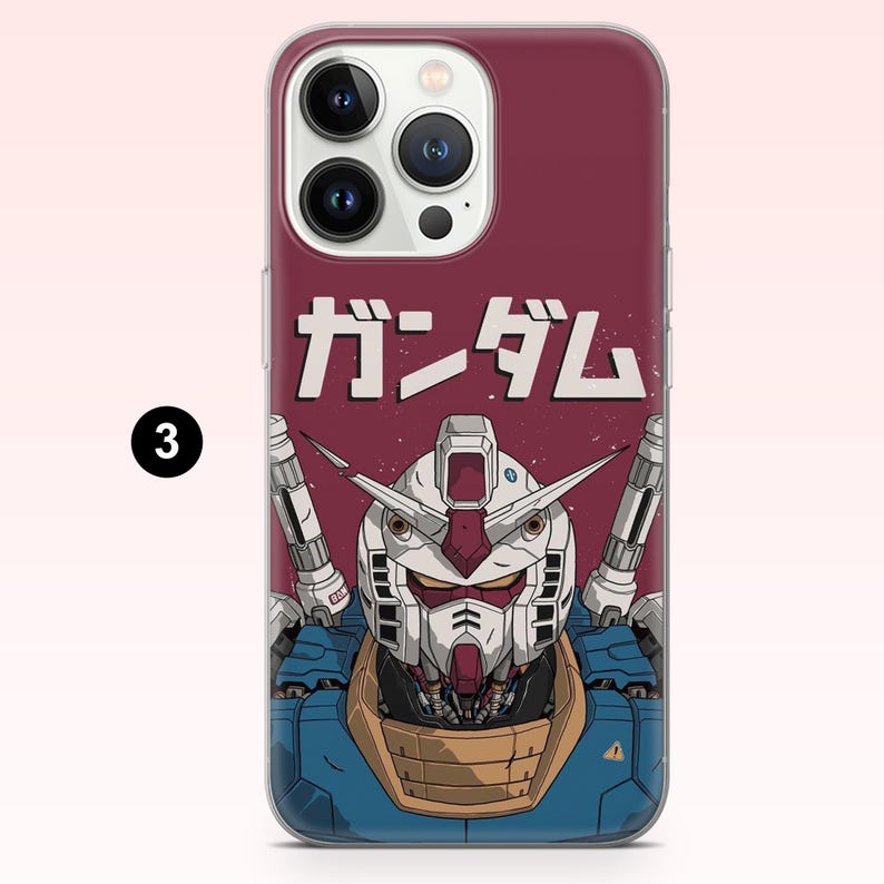 May include: A smartphone case featuring a graphic illustration of a white, blue, and tan robot head with antennae. Above the robot, the Japanese text ガンダム is printed in white against a solid dark red background. The case has a camera cutout.