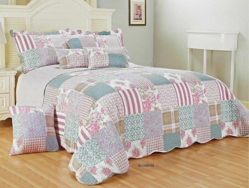 May include: A patchwork quilt and matching pillow sham set featuring a repeating pattern of floral prints, stripes, and geometric textures in shades of dusty rose, sage green, and cream. The quilt has a scalloped edge and the word BLOSSOM.