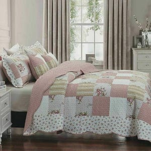 May include: A patchwork quilt and matching pillow shams featuring a repeating pattern of pink gingham, cream stripes, and floral prints. The bedding set has a scalloped edge and is displayed on a bed with white pillows and a white nightstand.