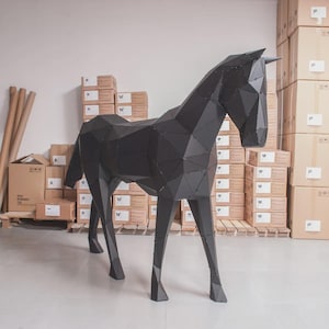 May include: A large, matte black horse sculpture constructed from numerous flat, geometric metal panels joined together. The sculpture features a faceted, low-poly design with visible rivets at the joints, standing on four slender, angular legs.