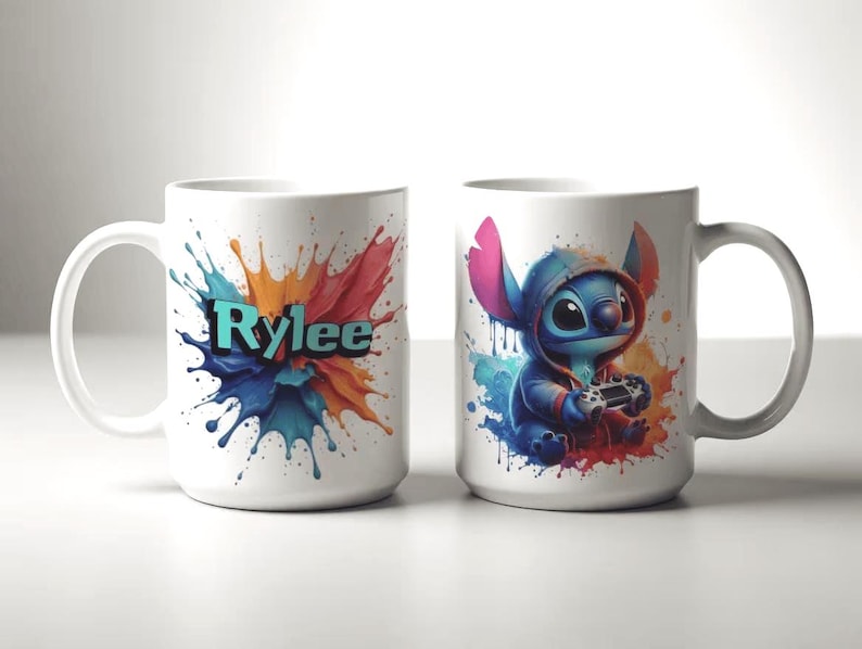 May include: Two white ceramic mugs. One mug features the name "Rylee" in teal letters against a colourful paint splash design. The other mug has a blue cartoon character wearing a hoodie and holding a game controller, with a paint splash background.