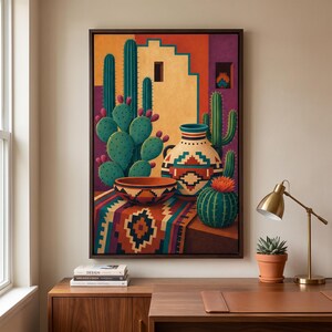 May include: A framed wall art print depicting a desert scene with prickly pear cacti, a round bowl, and a patterned vase on a colorful geometric textile. The background features adobe-style architecture in shades of orange, yellow, and purple.
