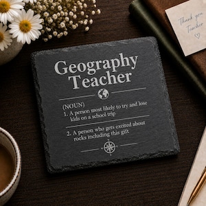 May include: A square black slate coaster featuring the engraved text Geography Teacher, followed by a dictionary-style definition with two points about losing kids on a school trip and getting excited about rocks, accented by globe and compass icons.