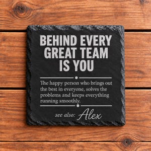 May include: A square black slate coaster with rough, chiseled edges. The text reads: BEHIND EVERY GREAT TEAM IS YOU. The happy person who brings out the best in everyone, solves the problems and keeps everything running smoothly. see also: Alex.