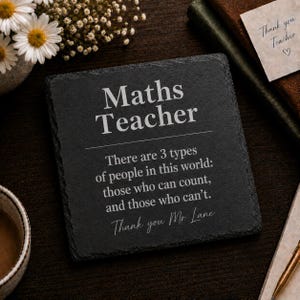 May include: A square black slate coaster featuring the engraved text: Maths Teacher. There are 3 types of people in this world: those who can count, and those who can't. Thank you Mr Lane. The coaster has a rough, textured edge and a matte finish.