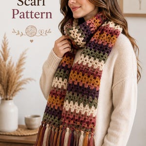 May include: A crochet scarf pattern featuring a multi-colored granny square design in shades of dark purple, olive green, mustard yellow, and cream. The scarf has long, thick fringe tassels at the ends in matching colors. Text reads Crochet Scarf Pattern.
