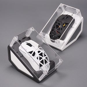 以下が含まれることがあります： 白と黒の2つのワイヤレスコンピュータマウス。それぞれスケルトン状の格子デザインのシェルを備えています。マウスは黒と白のベースが付いた傾斜のある透明なアクリル製ディスプレイケースに収められており、白いマウスにはRazerのロゴが刻印されています。