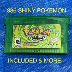 May include: A translucent green Game Boy Advance video game cartridge for Pokémon LeafGreen Version. The label features a swirling green background, the Pokémon logo, and the text 386 SHINY POKEMON INCLUDED & MORE! The ESRB E rating is visible.