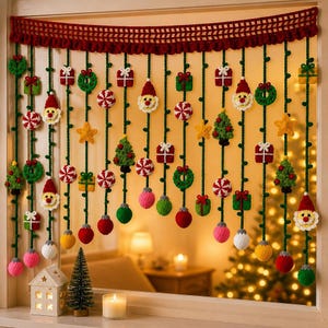 Op de afbeelding: Een decoratieve gehaakte raamdecoratie met een donkerrode geschulpte bovenrand en hangende groene garenstrengen. Aan de strengen zijn diverse gehaakte kerstornamenten bevestigd, waaronder kerstmannen, cadeautjes, kransen, sterren en kerstballen.
