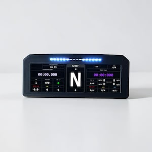 May include: A black digital display with multiple screens showing data. The display has a series of blue lights at the top. The screens show numbers and the text "Lap", "N/REF", and "CAT". The display is on a white surface.