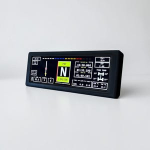 Könnte beinhalten: Ein schwarzes rechteckiges Digitaldisplay mit verschiedenen Datenausgaben, darunter Rundenzeiten, Reifentemperaturen und Kraftstoffstände. Der Bildschirm zeigt den Text "PIT" und "LIMITER". Der Hintergrund ist weiß.