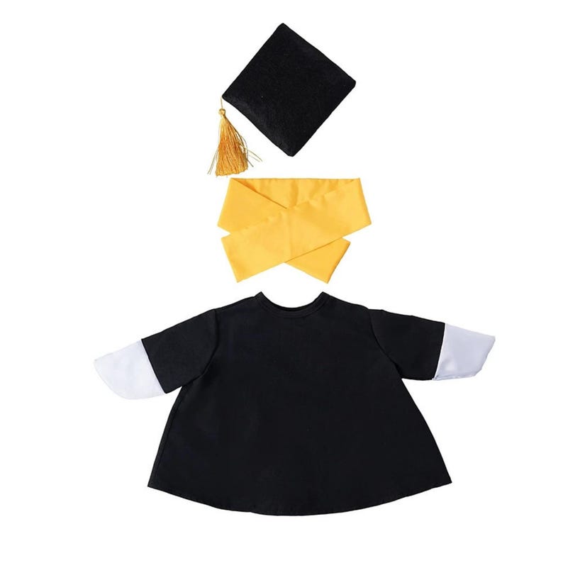 K&ouml;nnte beinhalten: Ein schwarzes Abschlusskleid-Set mit passender quadratischer Kappe, goldener Quaste und gelber Sch&auml;rpe. Das Kleid hat wei&szlig;e &Auml;rmel. Ideal f&uuml;r eine Abschlussfeier oder ein thematisches Fotoshooting.