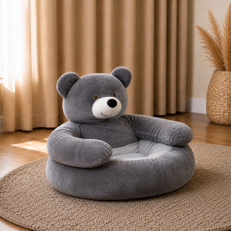 May include: A gray plush bear-shaped chair with a round seat and armrests. The bear has a white face, black nose, and small brown eyes. The chair is designed for children and is placed on a round, textured rug.