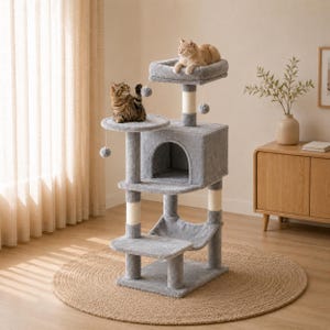 May include: A multi-level cat tree covered in soft grey plush fabric, featuring a square enclosed cubby, a top perch, a lower hammock, and several sisal-wrapped scratching posts. Three small grey pom-pom toys hang from the structure.