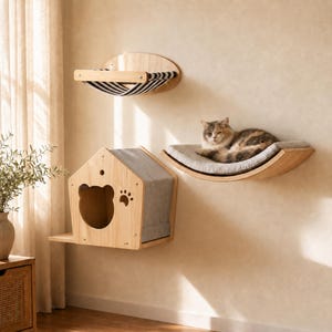 May include: A wall-mounted cat furniture set featuring a light wood house with a bear-shaped entrance and paw print cutout, a curved wooden shelf with a grey cushion holding a cat, and an oval wooden hammock with black and white stripes.