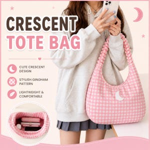 May include: A crescent-shaped tote bag featuring a pink and white gingham pattern with a white crescent moon patch. The bag has a gathered, ruched shoulder strap. The interior is shown in a circular inset, displaying a pink and white gingham lining.