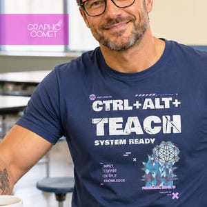 Könnte beinhalten: Ein marineblaues T-Shirt mit weißem, abgenutztem Text, der CTRL+ALT+TEACH und SYSTEM READY lautet. Weitere Aufschriften sind INPUT, COFFEE, OUTPUT, KNOWLEDGE, TEACHER OS V2.5 sowie eine geometrische Grafik eines stilisierten blauen Kaktus.