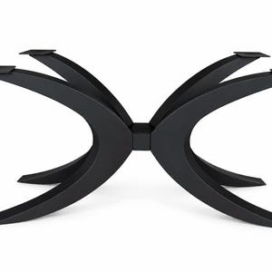 Könnte beinhalten: Ein mattschwarzes Tischgestell aus Metall mit einem zentralen quadratischen Verbindungsstück und vier geschwungenen Beinen, die nach außen ragen. Jedes Bein endet in einer flachen, quadratischen Montageplatte zur Befestigung einer Tischplatte.
