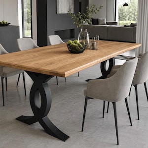 Peut inclure: Une table à manger rectangulaire avec un plateau en bois naturel brun clair et deux pieds en métal noir au design incurvé et entrelacé. Six chaises rembourrées gris clair avec des pieds en métal noir entourent la table.