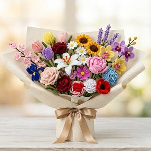 May include: A bouquet of crocheted flowers featuring a variety of blooms including pink and yellow tulips, red roses, white lilies, sunflowers, lavender, and purple orchids, all wrapped in beige paper and tied with a matching satin ribbon bow.
