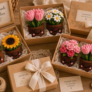 May include: Several gift boxes containing crocheted potted flowers with smiling faces. The flowers include pink tulips, white daisies, yellow sunflowers, purple lavender, and pink roses. Each box features white tissue paper, and some include labels with text like handmade with love, Just for you, and THANK YOU.
