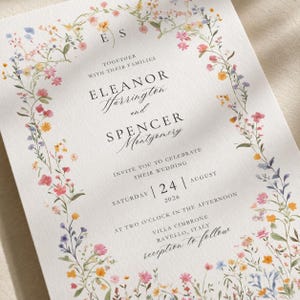 Close-up of floral wedding invitation printed on premium textured cotton cardstock highlighting delicate wildflower border and elegant typography.