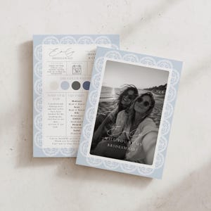 May include: A light blue bridesmaid proposal card featuring a white lace border design. The card displays a black and white photograph of two people on a beach, with the text Emily, will you be my bridesmaid? and wedding party details.