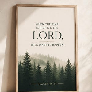 May include: A framed wall art print featuring a forest of dark green pine trees fading into a misty background. The text reads: WHEN THE TIME IS RIGHT, I, THE LORD, WILL MAKE IT HAPPEN. ISAIAH 60:22. The frame is made of light-coloured wood.