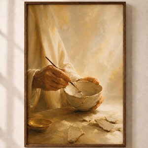 May include: A framed wall art print depicting a person in a cream-colored robe repairing a broken ceramic bowl with gold lacquer. The scene features a small gold dish, scattered ceramic shards, and a fine brush, rendered in warm, golden tones.