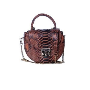 Puede incluir: Bolso de mano marrón y negro con estampado de piel de serpiente, con asa superior y bandolera de cadena. El bolso tiene forma curva, cierre metálico y asa pequeña. El bolso está sobre fondo blanco.