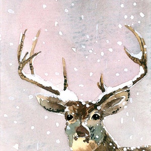 Könnte beinhalten: Ein Aquarellbild eines Hirsches mit Geweih, das mit Schnee bedeckt ist. Der Hirsch schaut direkt auf den Betrachter. Der Hintergrund ist zartrosa mit weißen Schneeflocken.
