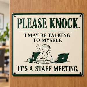 May include: A rectangular sign with a cream background and dark green border. The text reads: PLEASE KNOCK. I MAY BE TALKING TO MYSELF. IT'S A STAFF MEETING. An illustration shows a dog wearing glasses at a desk with a laptop and a mug.