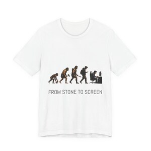 Könnte beinhalten: Ein weißes kurzärmeliges T-Shirt mit einem Grafikdruck, der die Evolution der Menschheit vom Primaten bis hin zu einer Person vor einem Computer zeigt. Unter der Grafik steht der Text FROM STONE TO SCREEN in einer einfachen schwarzen Schrift.