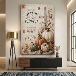 May include: A vertical wall art print featuring a wooden cross, various pumpkins, and autumn leaves. The text reads: In every season God remains faithful, He fills our hearts with peace and our lives with purpose, Lamentations 3:22-23. The color palette includes cream, orange, and muted green tones.