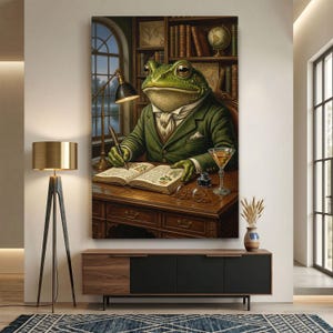 May include: A wall art print depicting a green frog wearing a dark green suit and white cravat, sitting at a wooden desk in a library. The frog is writing in an open book with a fountain pen, with a martini glass, inkwell, and glasses nearby.