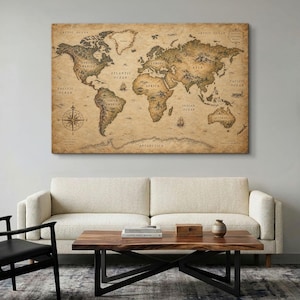 Op de afbeelding: Een rechthoekige wandkunstprint met een wereldkaart in vintage-stijl met een esthetiek van sepia-kleurig perkamentpapier. De kaart toont continenten, oceanen en bergschetsen, met een kompasroos in de linkerbenedenhoek.