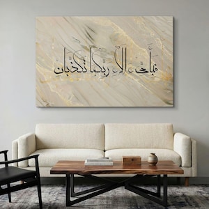 May include: A rectangular wall art piece featuring a beige and cream marble-like background with gold veining accents. Black Arabic calligraphy is centered across the surface, displaying the text: فَبِأَيِّ آلَاءِ رَبِّكُمَا تُكَذِّبَانِ.