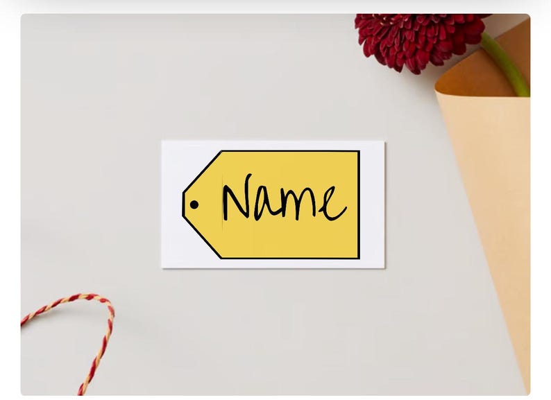 May include: A white card with a yellow tag that says "Name" in black cursive writing. The tag has a black circle in the upper left corner.