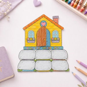 May include: A yellow house-shaped paper cutout with an orange roof, a brown door, and a blue chimney. The text "BUILD YOUR LIFE ON JESUS" is printed on a blue banner above six gray stone-shaped sections for writing, with a pink heart above the door.