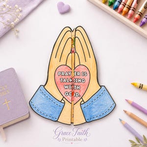 Puede incluir: Una manualidad de papel de dos manos juntas en oración, coloreadas con tonos de piel bronceados y mangas azules. Un corazón rosa en el centro presenta el texto PRAYER IS TALKING WITH GOD. La manualidad está dividida por la mitad con bordes negros.