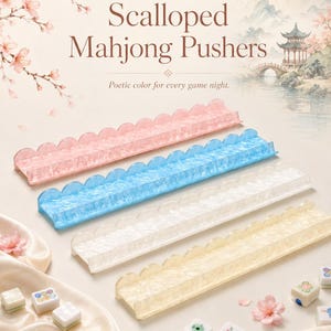 May include: Four scalloped Mahjong pushers in pink, blue, white, and yellow. The pushers are rectangular with a wavy edge. The image includes Mahjong tiles and the text "Scalloped Mahjong Pushers" and "Poetic color for every game night."