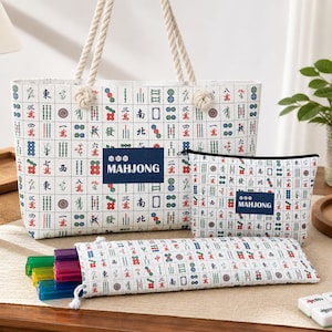 May include: A white tote bag, a zippered pouch, and a long rectangular case, all featuring a repeating grid pattern of colorful mahjong tiles. Each item includes a dark blue rectangular patch with the white text MAHJONG printed on it.
