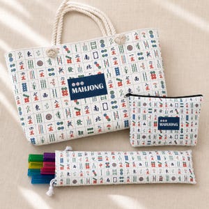 May include: A white tote bag, a rectangular zippered pouch, and a long narrow case, all featuring a repeating pattern of colorful mahjong tile symbols. Each item has a dark blue rectangular patch with the white text MAHJONG printed on it.