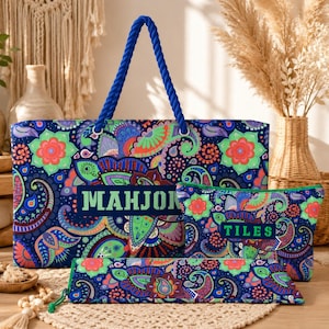 May include: A large rectangular tote bag, a smaller zippered pouch, and a long slim case, all featuring a vibrant blue, green, orange, and purple paisley pattern. The tote has blue rope handles and the text MAHJONG. The pouch features the text TILES.