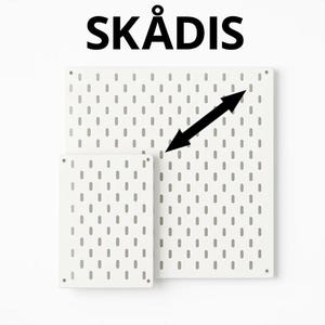 May include: Two white rectangular pegboards labelled SKÅDIS with a repeating pattern of vertical oval slots. A black double-headed arrow is positioned diagonally across the larger board to indicate its span. Both boards feature small circular corner holes.