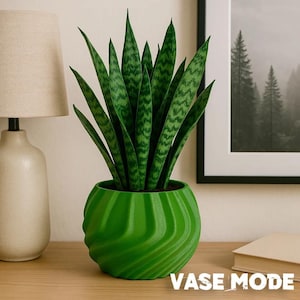 May include: A vibrant green, spiraled, 3D-printed planter containing a tall snake plant with variegated dark and light green leaves. The planter features a distinct ribbed, wave-like texture and sits on a flat surface with the text VASE MODE.